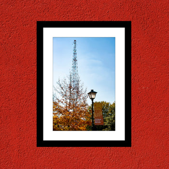 A framed artwork featuring a radio tower in Decatur Alabama, with a red background and a blue sky.