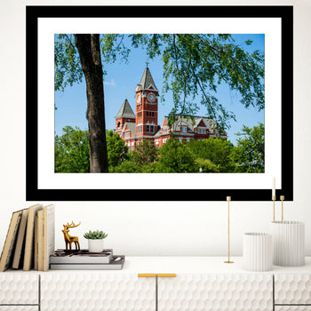 A framed art print featuring Samford Hall, Auburn University, with a clear blue sky and greenery in the background.