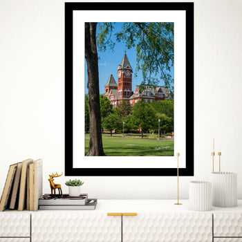 A framed art print featuring a photograph of Samford Hall, Auburn University, with a clear blue sky and greenery in the background.