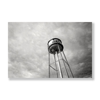 Black and white photo of a water tower with a cloudy backdrop.