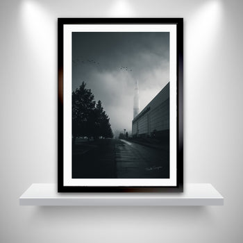 A black and white photograph of the Saturn V rocket in Huntsville, Alabama, displayed as a wall art piece on a white shelf with a gray background.