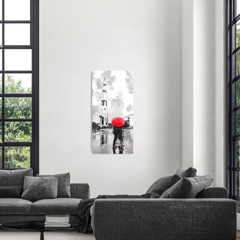 A black and white photograph of a couple kissing under a red umbrella, displayed on a wall above a grey sofa, with a large window behind them.