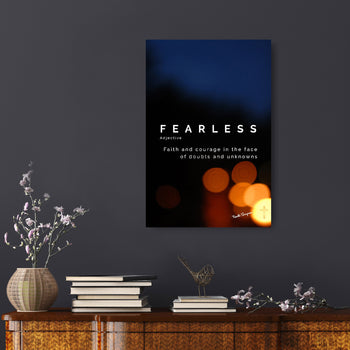 A canvas with the word 'FEARLESS' printed on it, displayed on a wall above a table with books and decorative items.
