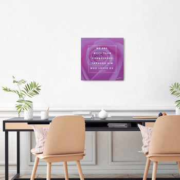 A canvas print with a purple rose and text, hung on a wall in a room with two chairs, decorative plants, and a table.