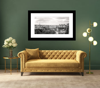 A black and white photograph of Downtown Huntsville Alabama, displayed in a frame, with a couch and lamp in the foreground.