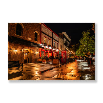 Night photography of Poppy and Parliament restaurant in Downtown Huntsville featuring a glowing red phone booth and rain-lit street.