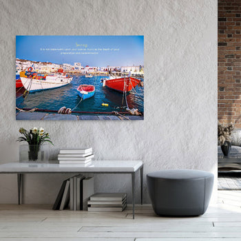 A motivational canvas art piece depicting a colorful scene of boats in a harbor with a quote about success, placed above a modern console table in a home setting.