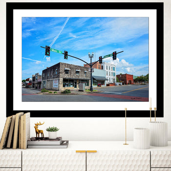 A framed photograph featuring an aerial view of a town square in Moulton, Alabama, with a blue sky, green and red traffic lights, and storefronts.