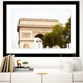 A framed art print featuring the Top of Arc de Triomphe in Paris, displayed on a wall above a modern white console table with a plant and decorative items.